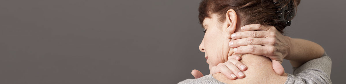 Frau grift sich an den Nacken und Hals